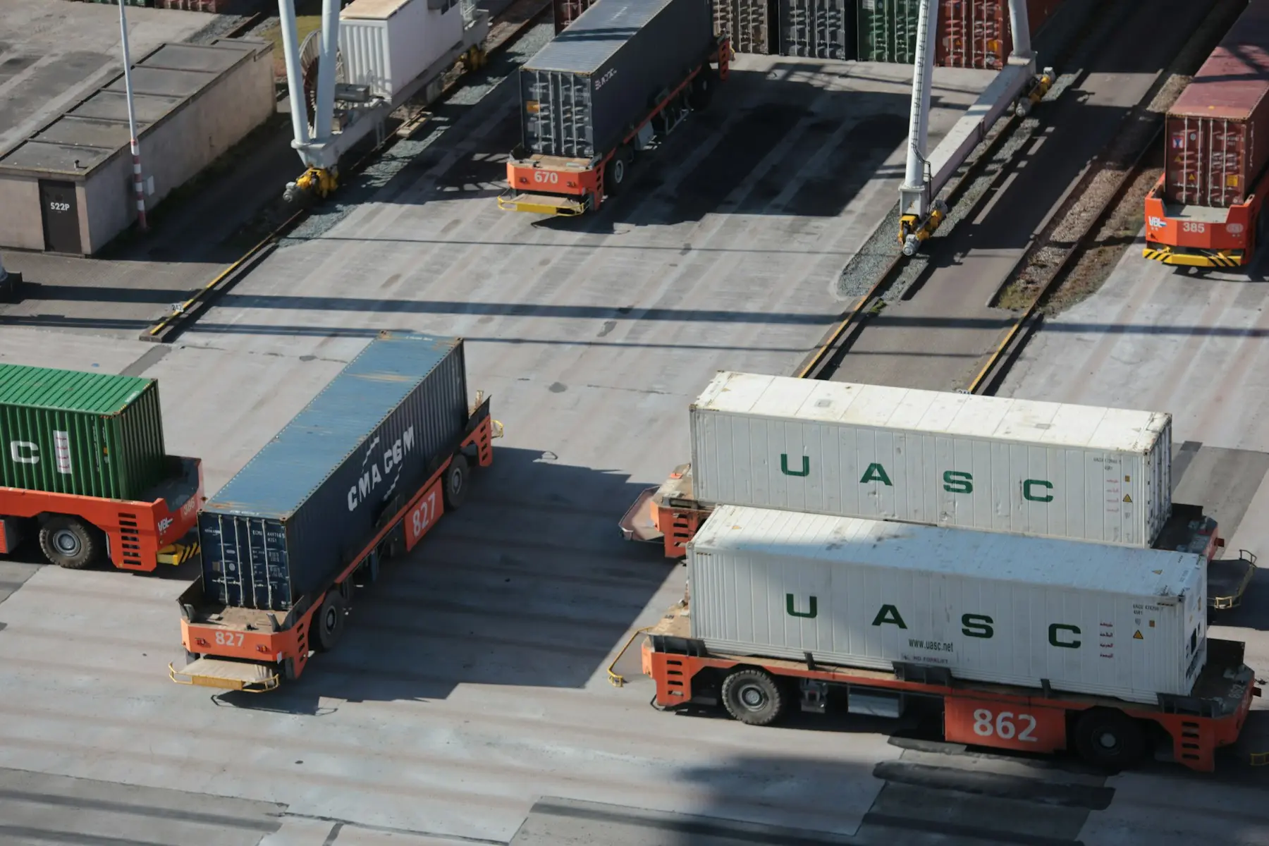Port crane lifting containers above trucks at a terminal