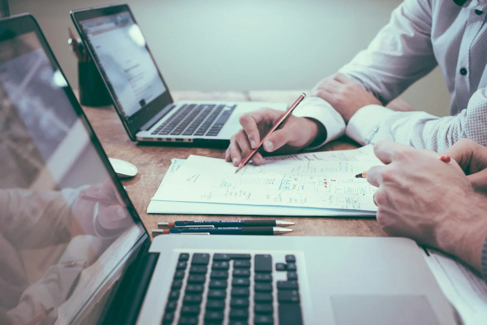 Shipping documents being reviewed at a desk alongside a laptop